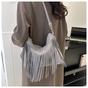 Detailed view of gray faux leather crossbody bag with swaying fringe and gold hardware