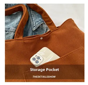 Close-up of brown corduroy tote bag featuring a front storage pocket and magnetic snap button