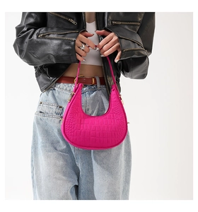 Fuchsia halvemaanvormige tas met krokodillenpatroon gedragen met een leren jasje