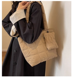 Détail d'un sac cabas matelassé beige avec mini pochette assortie porté par un mannequin