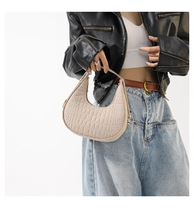 Detail van de beige maanvormige tas met krokodillenpatroon gestyled op een fotomodel