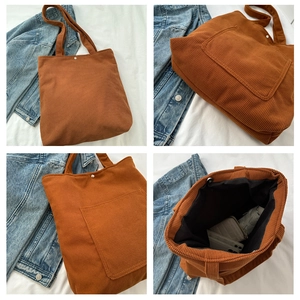 Detail view of large corduroy tote bag showing metal magnetic buckle and spacious interior