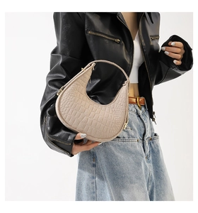 Detail van de beige hobo-tas met krokodillenprint en een stoer leren jasje