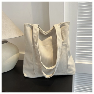 Gros plan du sac cabas en velours côtelé crème montrant la texture et la poche avant