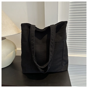 Détail du cabas en velours côtelé noir avec texture rayée et poche avant pratique