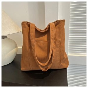 Détail d'un grand sac cabas en velours côtelé marron avec poche frontale élégante