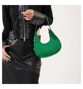 Model draagt een groene hobo-tas met krokodillenprint, gouden details en halvemaanvorm