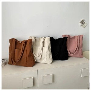 Row of four colorful corduroy tote bags with large front pockets and twin straps