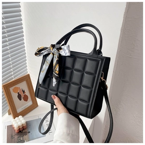 Detail of black embossed tote bag with chic silk scarf and quilted square texture