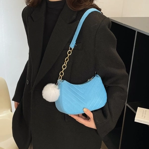 Blue hobo shoulder bag with V-shaped quilting, gold chain and white fur pompom charm