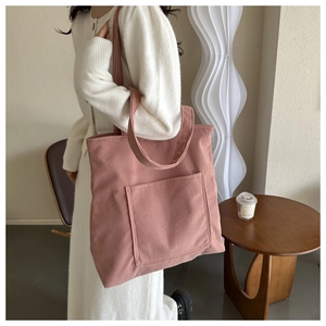 Detail view of the pink corduroy tote bag showing its ribbed texture and front pocket