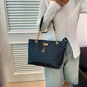 Large tote bag with clover pattern and gold chain strap shown on model's shoulder