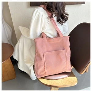 Détail du sac fourre-tout en velours rose avec large bandoulière et bouton-pression en métal