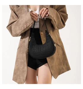 Modieuze zwarte hobo tas met steentextuur gedragen door een model in een bruine blazer