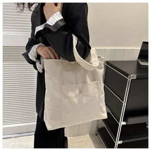 Detail of cream corduroy tote bag with ribbed texture and square front pocket