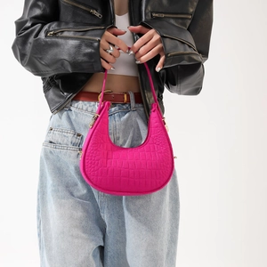 Fuchsia halve maan tas voor dames met krokodillenprint gedragen over een zwart jasje