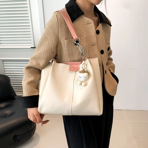 Minimalist beige tote bag with pink leather straps and plush charm in a lifestyle shot