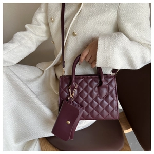 Detail of wine red quilted handbag with golden hardware and matching mini pouch accessory