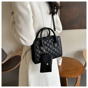 Detail of black quilted leather crossbody bag with matching detachable pouch accessory