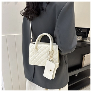 Detailed view of white quilted crossbody bag with matching mini pouch and gold hardware