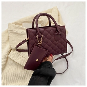Detail of burgundy quilted leather square handbag with golden chain and mini pouch