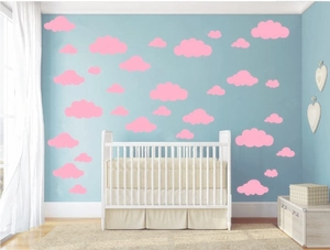 Pink cloud wall stickers in various sizes arranged above a crib in a baby nursery