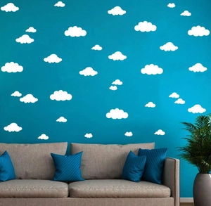 Detailed view of white cloud wall stickers on a navy blue wall in a cozy bedroom setting