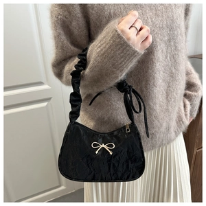 Detail of black pleated cloud bag with golden butterfly buckle and ruffled shoulder strap