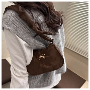 Detail of brown pleated shoulder bag featuring a golden butterfly metal buckle accent
