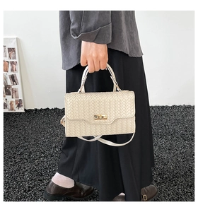 Detail der cremefarbenen Flecht-Handtasche mit Metalldrehverschluss und Griff
