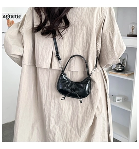 Detail of black semi-circle bag featuring chic bow and metal ball charms on PU leather