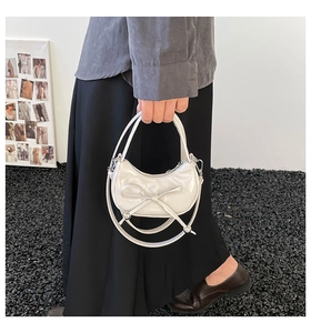 Detail of white pearl dumpling bag with oversized bow and metallic silver ball accents