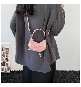 Sac rose en cuir verni porté par un mannequin avec nœud, sangle et détails en perles