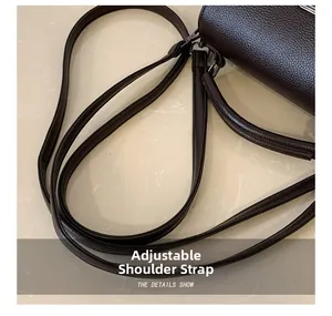 Macro shot of adjustable leather shoulder strap with gold metal buckles on a dark brown bag