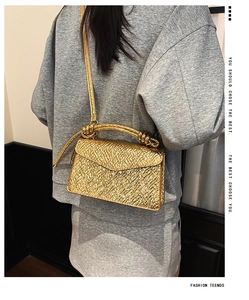 Detailed view of golden metallic crossbody bag with textured hammered finish and braided handle