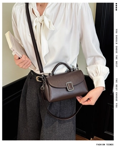 Close-up of premium dark brown lychee texture leather handbag with silver metal buckle