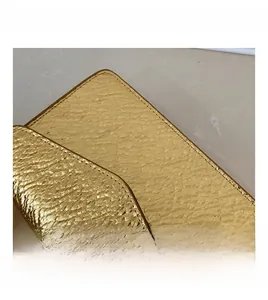 Detailed close-up of golden embossed scale texture and stitching on minimalist square bag