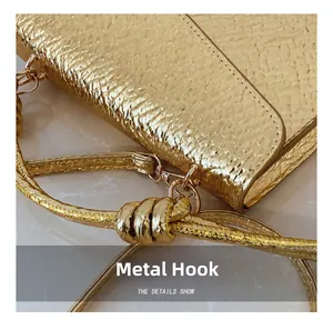 Detail of golden textured handbag showing the hardware hook and metallic scale pattern