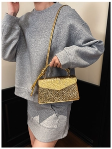 Detailed view of the knotted handle and metallic wrinkled texture on the gold square bag