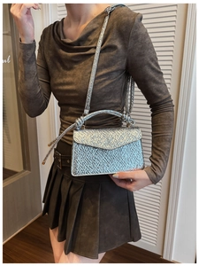 Detail of silver metallic crossbody bag with gathered texture and knotted handle