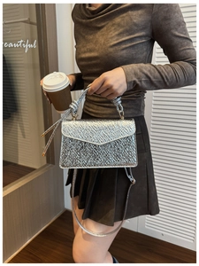 Detail of silver metallic textured crossbody bag with pleated handle on a model