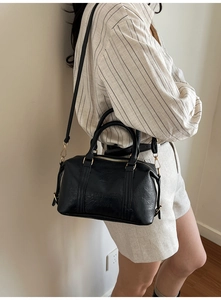 Detalle de bolso Boston de cuero negro con texto FASHION PARIS y correa ajustable