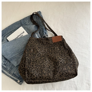 Détail du sac cabas léopard en toile avec rivets métalliques et écusson en cuir marron