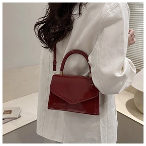 Details der weinroten Lackleder-Handtasche mit goldener Schließe und Klappendesign