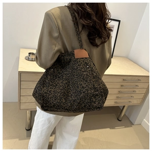 Détail du sac cabas léopard avec empiècement en cuir marron et finitions en rivets métal