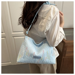 Gros plan du sac bandoulière bleu clair avec broderies colorées et écusson mode