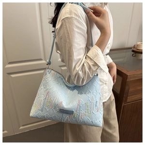Détail du sac seau bleu clair à rayures avec coutures colorées et étiquette mode