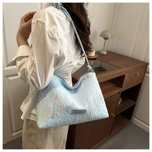 Gros plan du sac hobo bleu clair avec broderie vagues et étiquette logo FASHION