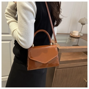 Detailansicht der glänzenden braunen Lackledertasche mit verstellbarem Schultergurt