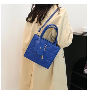 Blue quilted handbag with matching pouch accessory and metal tassel on a stylish model
